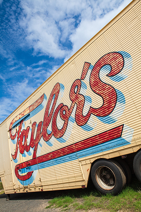 An image of eroded typographic sign writing on the side of a truck with a background of blue sunny sky